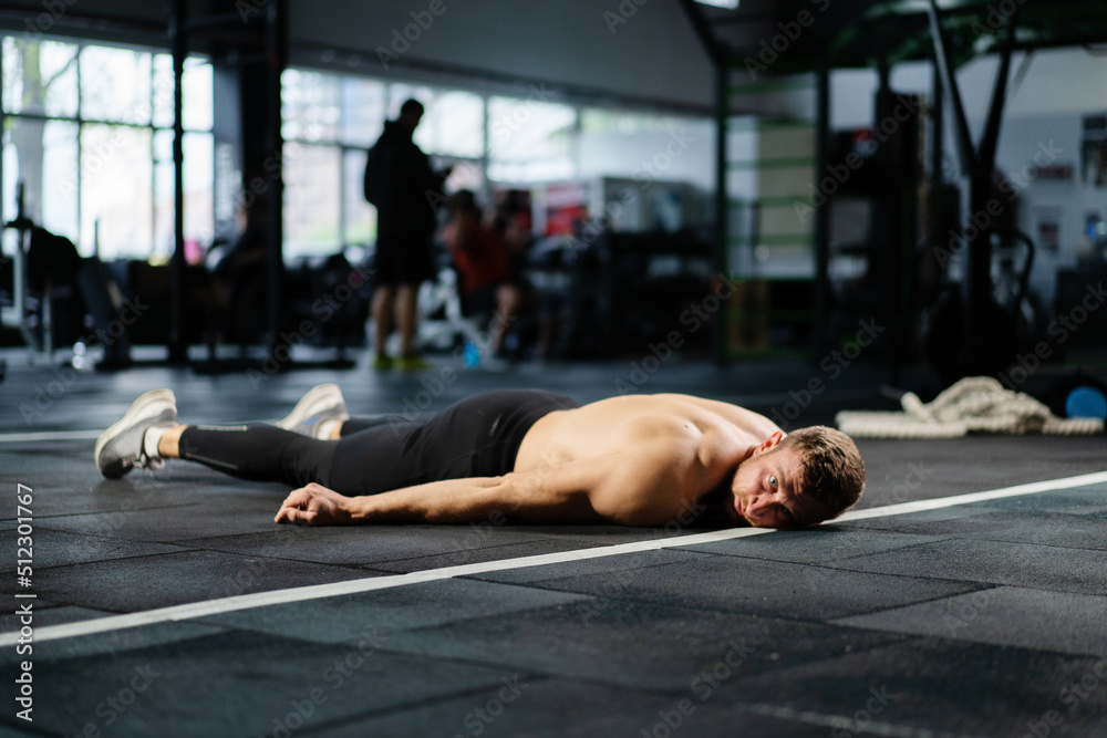 a man resting lies on the floor in the gym he is very tired and feels bad after a workout cross fit Stock Adobe Stock