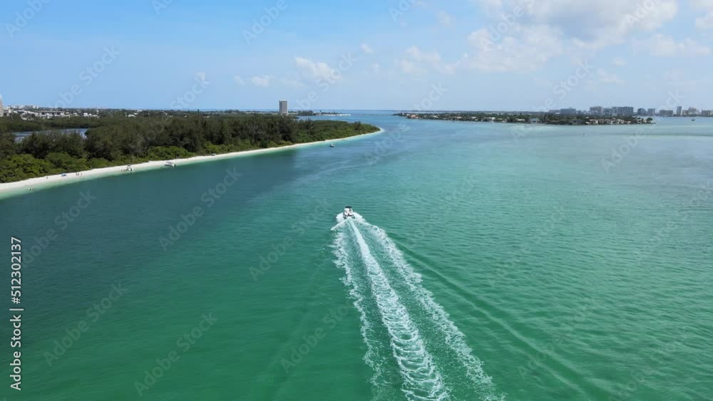 Camera catches up to a boat driving along the beach in coastal Florida. The boat is moving at full throttle creating a wake in crystal clear blue water. Camera catches up to a boat driving along the beach in coastal Florida. The boat is moving at full throttle creating a wake in crystal clear blue water.