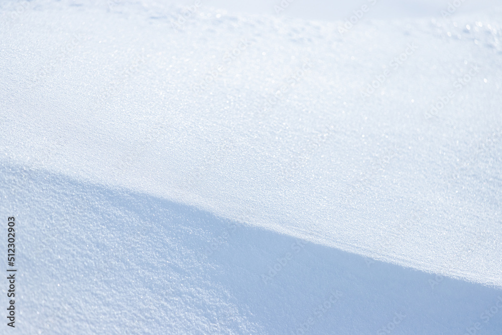 Beautiful winter background with snowy ground. Natural snow texture. Wind sculpted patterns on snow surface. Closeup top view with copy space.