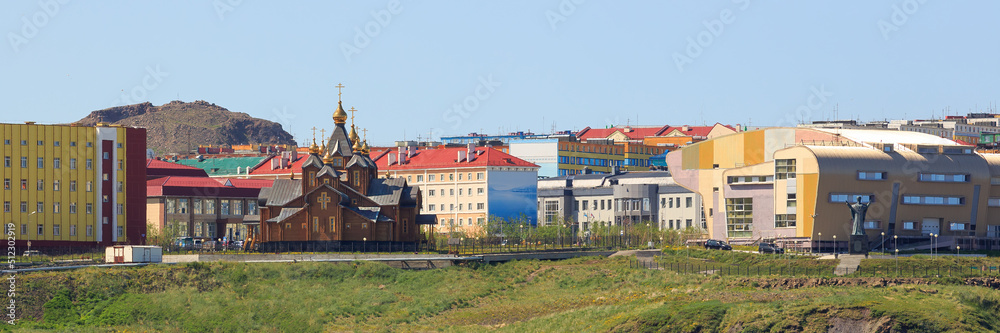 Summer panorama of a northern town in the Arctic. View of a large wooden cathedral and colorful buildings. Beautiful cityscape. City of Anadyr, Chukotka Autonomous Okrug, Far East of Russia.
