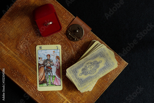 The layout of Tarot cards before making a difficult decision, getting married, getting engaged. A deck of fortune-telling cards on an old spell book and a casket with an engagement ring