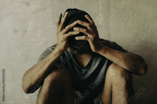 A drug addicted homeless man sitting alone and depressed in an abandoned house feeling anxious and lonely.