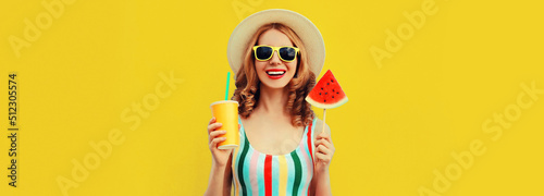 Summer portrait of happy smiling young woman with lollipop or ice cream shaped slice of watermelon and cup of juice wearing straw hat on yellow background, blank copy space for advertising text