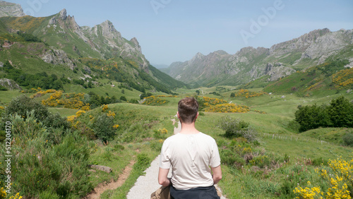 Hombre blanco de ruta en caballo por valle verde entre montañas rocosas photo