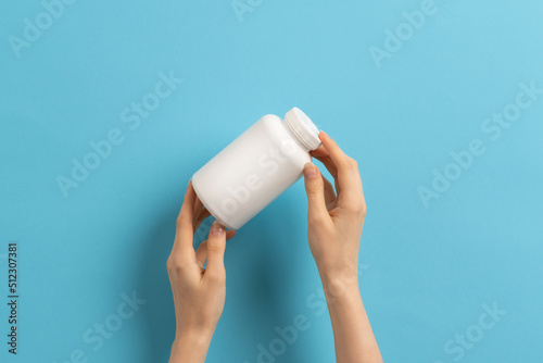 Female hand holding bottle of medication pills