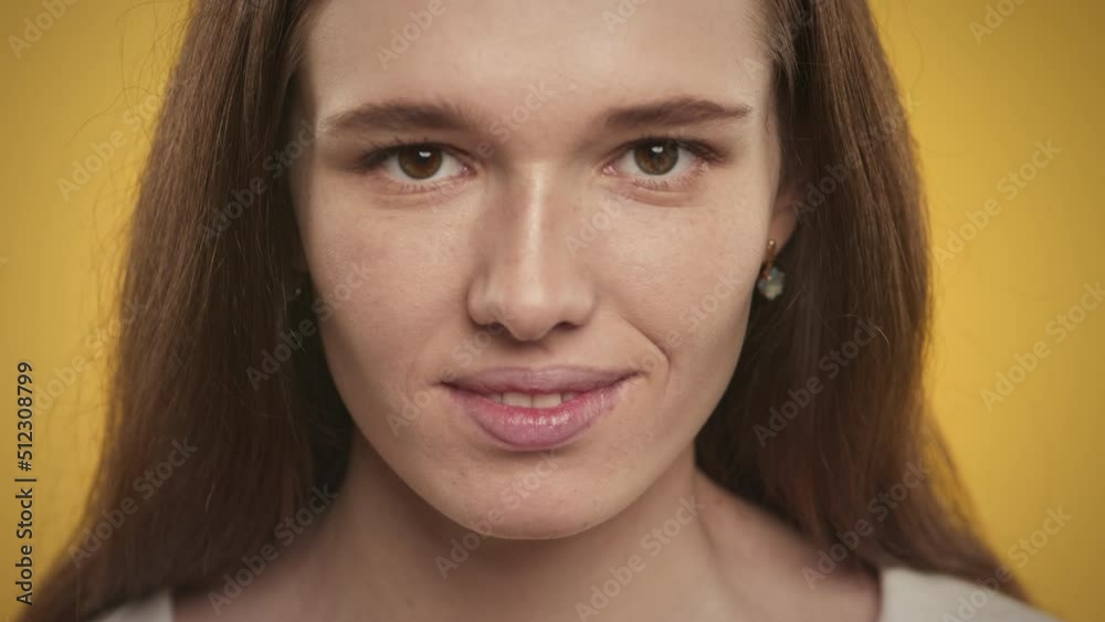 Extreme close up of a smiling caucasian young adult woman on yellow background