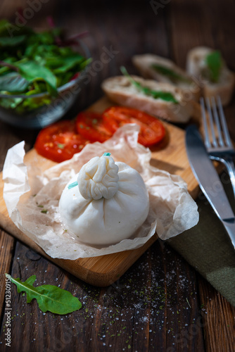 Fresh soft white burrata cheese ball made from mozzarella and cream from Apulia, Italy, close up