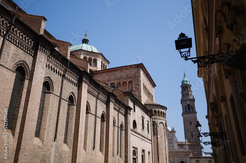 Side wall of Parma Cathedral and bell tower of Church of San Giovanni Evangelista also known as Abbazia di San Giovanni Evangelista. Vintage lanterns on street of old town and city highest bell tower