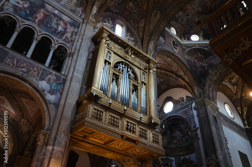 Parma, Italy - May, 2022: Musical organ in Parma Cathedral or Cattedrale di Santa Maria Assunta and renaissance frescoes on wall and ceiling. Main organ of Cathedral of Parma named Mascioni opus 1152