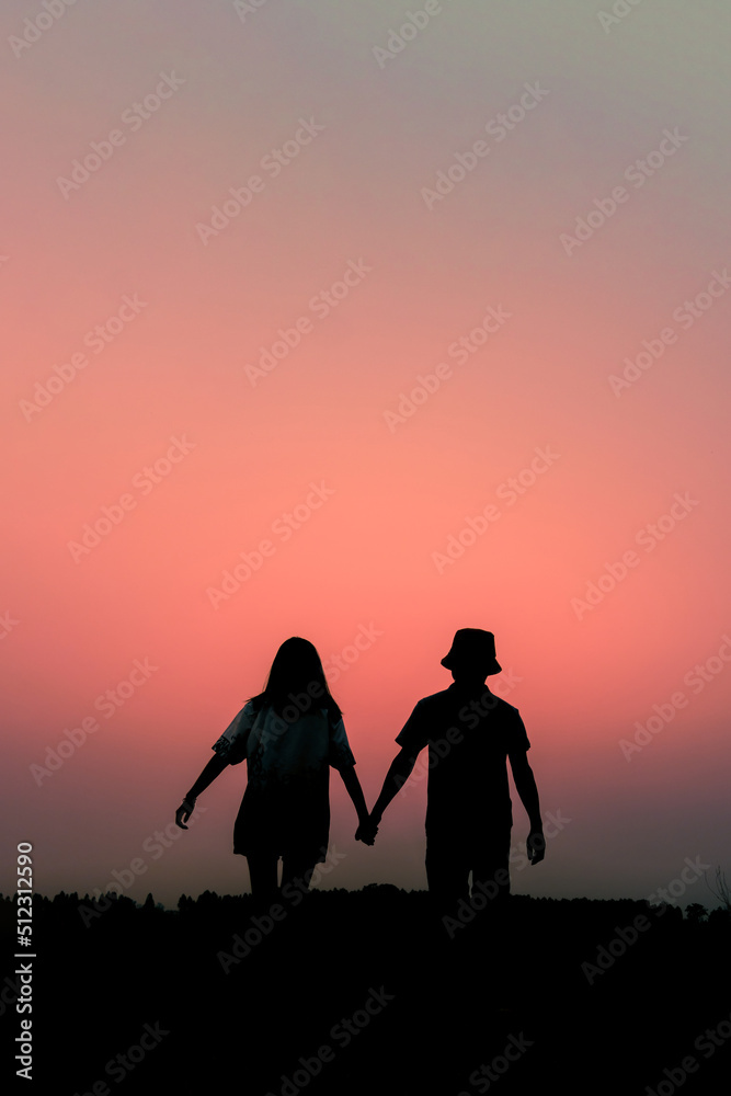 silhouette of a romantic couple enjoying beautiful sunset on outdoors.