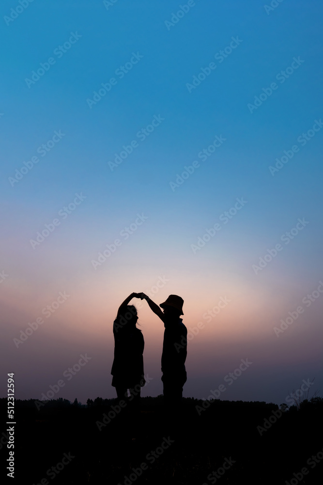 silhouette of a romantic couple enjoying beautiful sunset on outdoors.