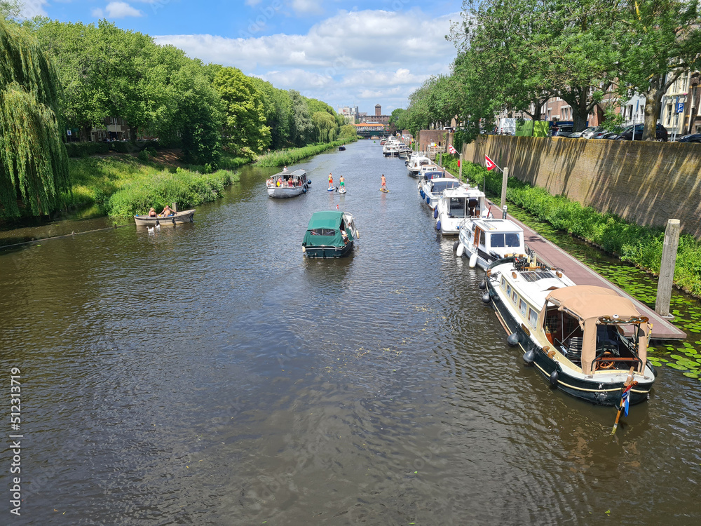 Naklejka premium Water recreationists on the Dommel enjoying the sunny weather. Seen from the Wilhelminabridge in Den Bosch.