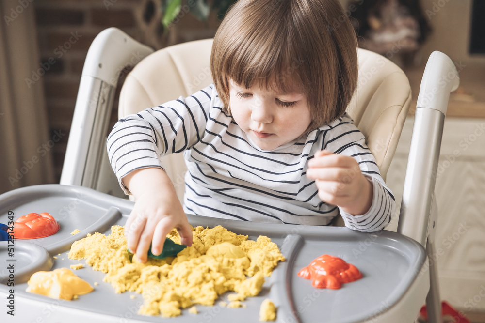 Cute little boy playing with kinetic sand. Development of fine motor skills. Early sensory education. Activities Montessori. Sensory plays at home.