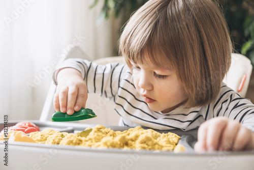 Cute little boy playing with kinetic sand. Development of fine motor skills. Early sensory education. Activities Montessori. Sensory plays at home.
