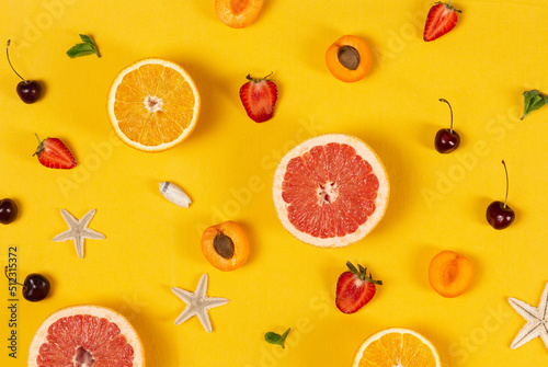Fototapeta Naklejka Na Ścianę i Meble -  Sliced fruits and berries with seashells and starfish on bright yellow background