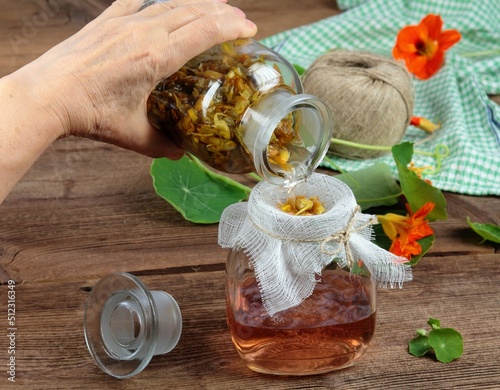 Fotografia Filtering tincture from Tropaeolum majus, also called garden nasturtium or Indian cress