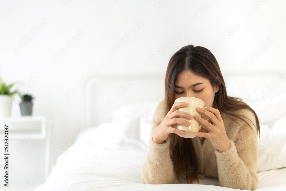 Portrait of smiling happy cheerful beauty pretty asian woman relaxing drinking and looking at cup of hot coffee or tea.Girl felling enjoy having breakfast in holiday morning vacation on bed at home Portrait of smiling happy cheerful beauty pretty asian woman relaxing drinking and looking at cup of hot coffee or tea.Girl felling enjoy having breakfast in holiday morning vacation on bed at home
