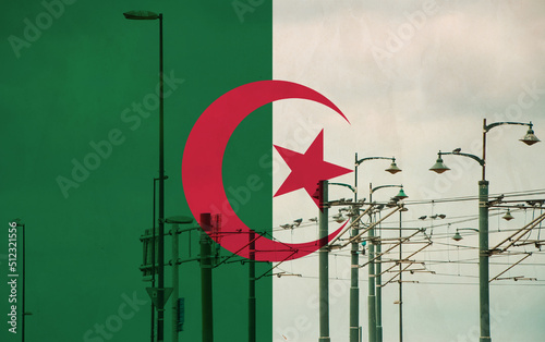 Algeria flag with tram connecting on electric line with blue sky as background, electric railway train and power supply lines, cables connections and metal pole overhead catenary wire