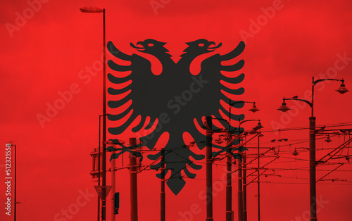 Albania flag with tram connecting on electric line with blue sky as background, electric railway train and power supply lines, cables connections and metal pole overhead catenary wire