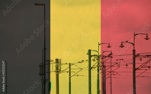 Belgium flag with tram connecting on electric line with blue sky as background, electric railway train and power supply lines, cables connections and metal pole overhead catenary wire