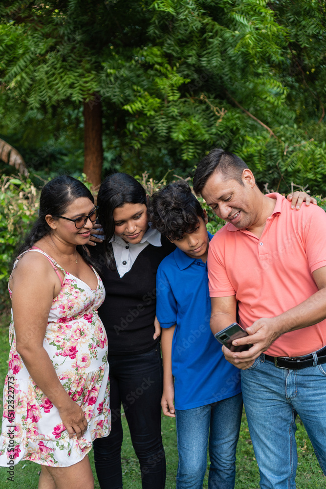 Latino family with two teenagers uses cell phone to make a video call