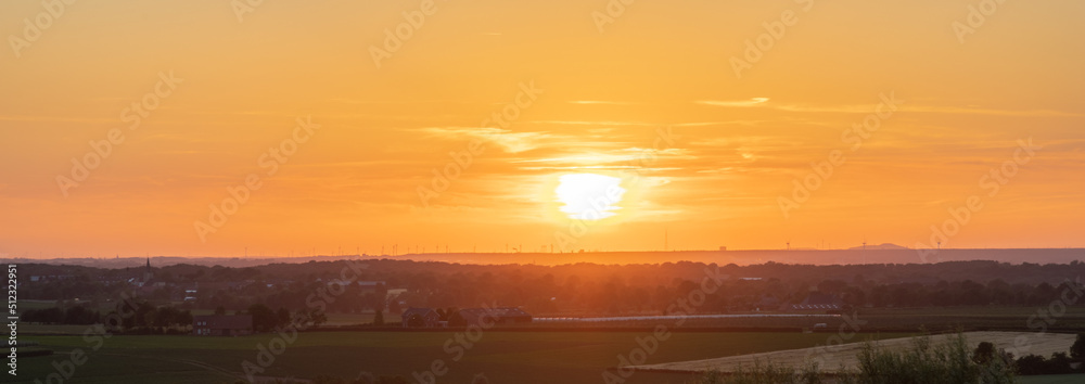 Obraz premium A golden sunset over the rolling hills in Banholt, south Limburg in the Netherlands creating holiday vibes. The views and the warm glow over the landscape create a feeling of being in the Mediterranea