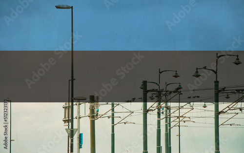 Estonia flag with tram connecting on electric line with blue sky as background, electric railway train and power supply lines, cables connections and metal pole overhead catenary wire