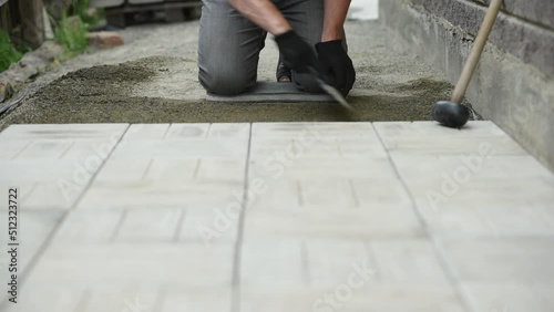 Man putting on work gloves before laying paving slabs photo