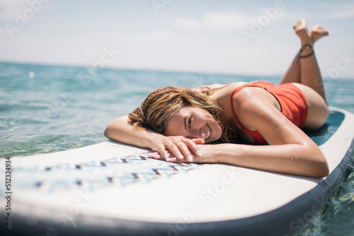 Smiling woman enjoys sunbathing on paddle board