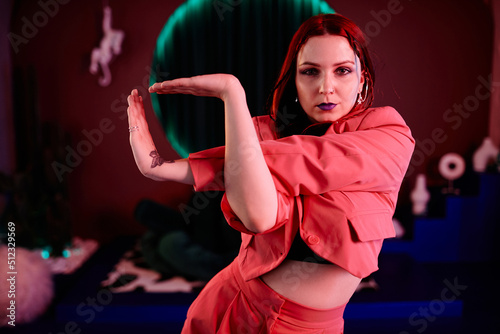 Photos Waist up portrait of young woman dancing vogue style in pink neon light with foc