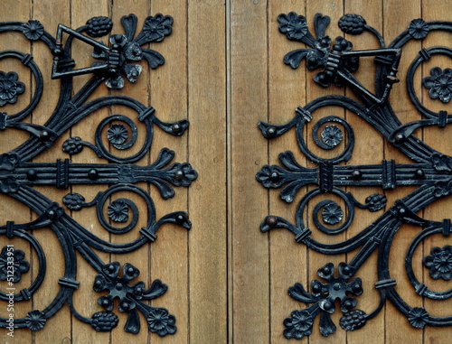 Wooden door with metal handles with lack floral ornaments. St Colman's Cathedral Cobh Ireland