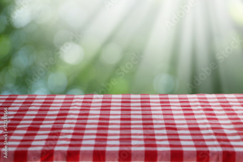 Table with checkered picnic cloth outdoors on sunny day. Space for design