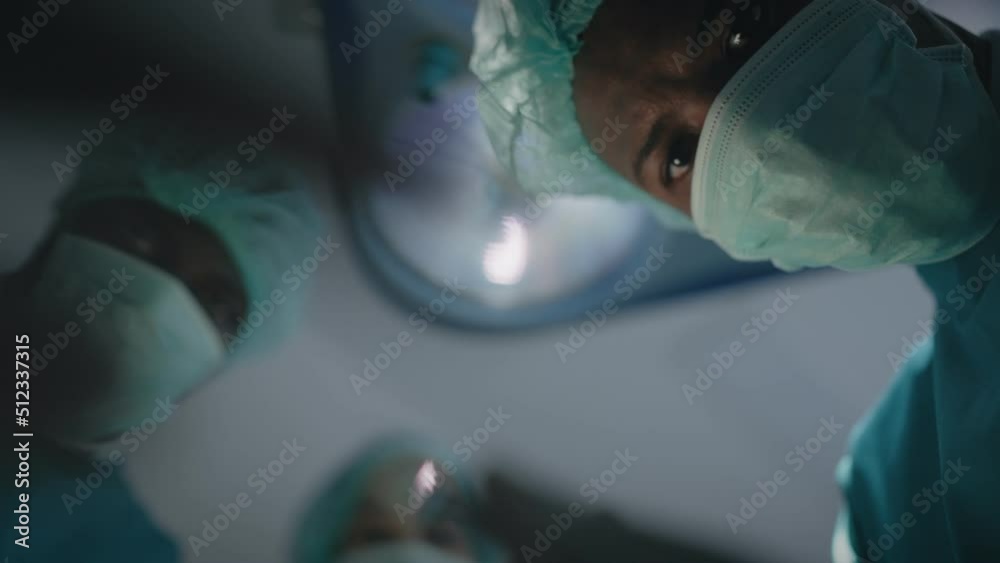 Point of view of patient with African American teams surgeons processing surgical operation looking into the eye for treatment in operating room hospital emergency department, POV eye blinking effect.