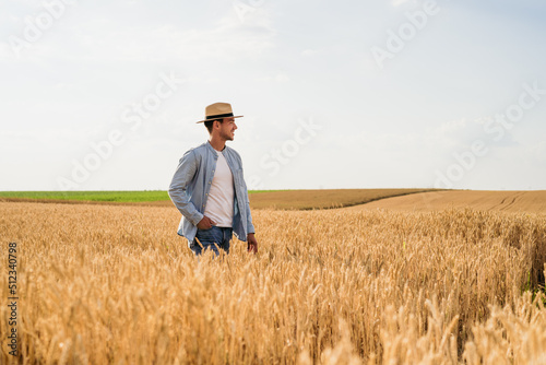 Happy farmer is standing in his growing wheat field. © inesbazdar