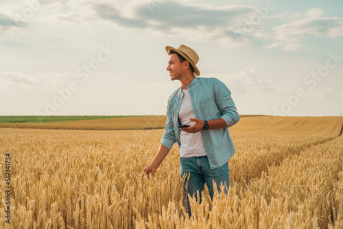 Happy farmer using mobile phone while standing in his growing  wheat field.  © inesbazdar