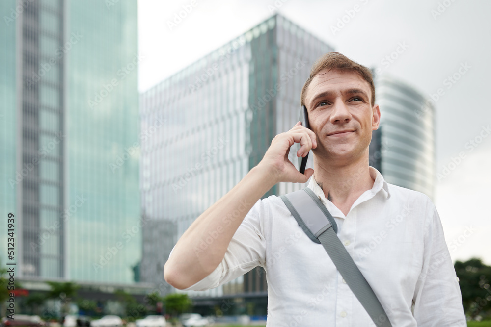Portrait of smiling man with bag over shoulder talking on phone Portrait of smiling man with bag over shoulder talking on phone