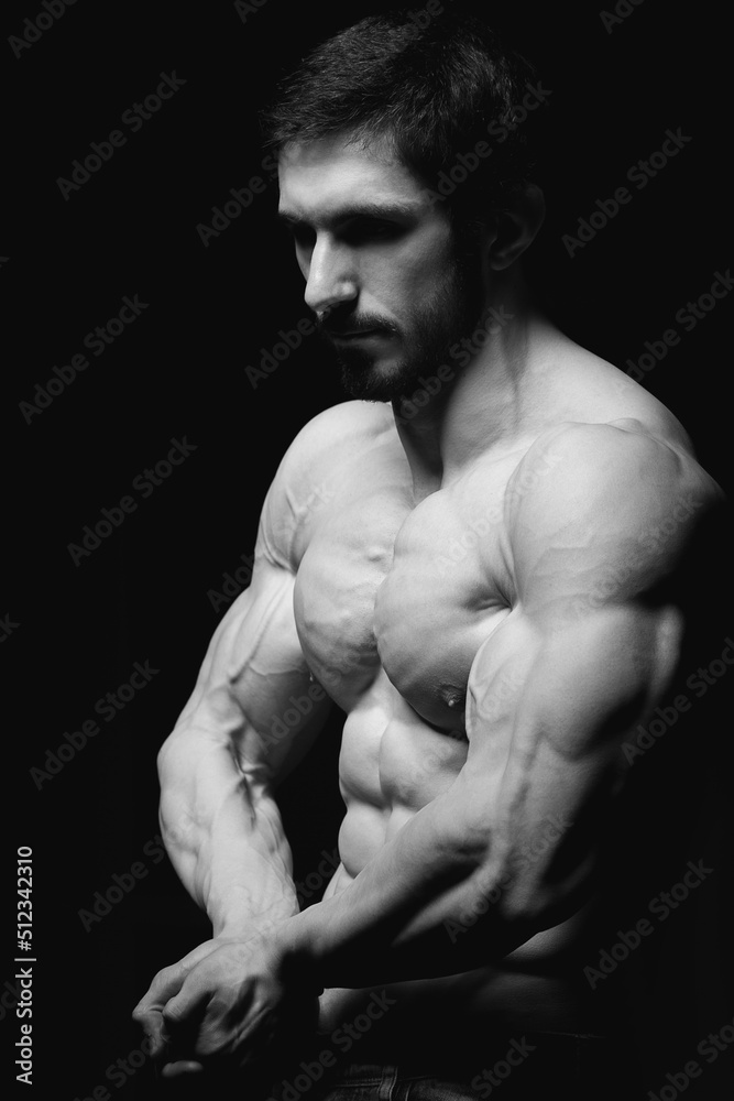 Portrait of shirtless muscular man in a jeans. Young male hunk showing his perfect body and muscles on black background Portrait of shirtless muscular man in a jeans. Young male hunk showing his perfect body and muscles on black background