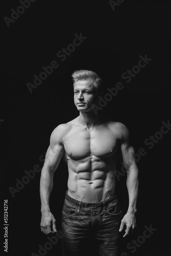 Fitness concept. Muscular and fit torso of young man having perfect abs, bicep and chest. Male hunk with athletic body on black background