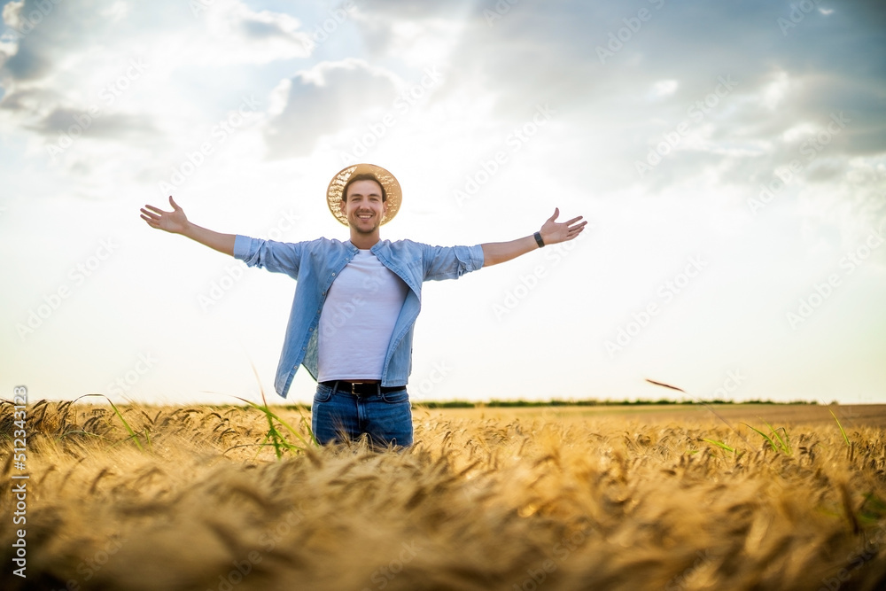 Happy farmer with arms outstretched standing in his growing barley field.