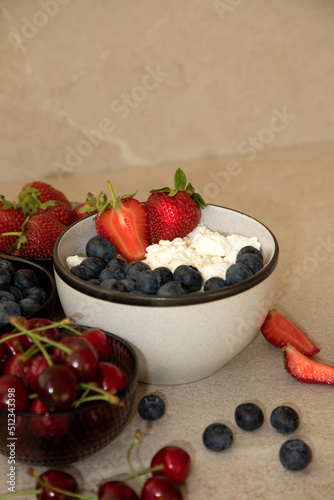 Curd with fresh blueberries and strawberries in a plate on a beige background. Healthy breakfast, front view photo