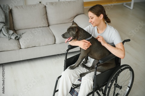 Young woman in wheelchair with dog indoors
