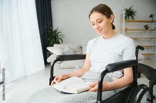Woman in wheelchair reading book at home
