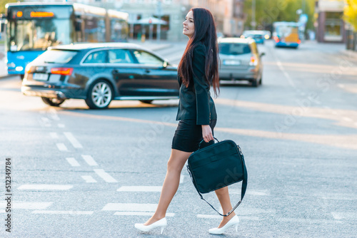 Young pretty business woman commuting and walking in city street with laptop bag.Side view,copy space.full-length.