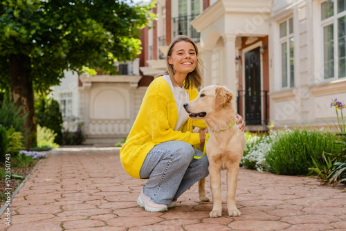 happy smiling woman in yellow sweater walking at her house with a dog golden retriever