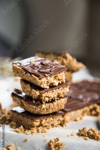High energy oatmeal bars or squares, made with oatmeal, peanut butter, honey, coconut oil, and cashews, topped with chocolate. Close view and shallow depth of field.