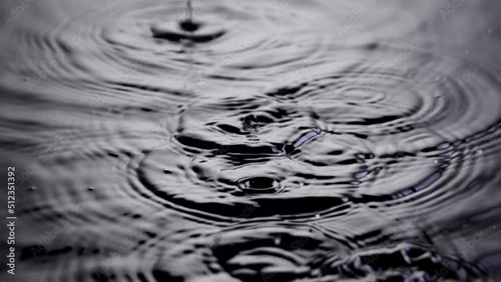 Slow motion shot of rain falling into a puddle.