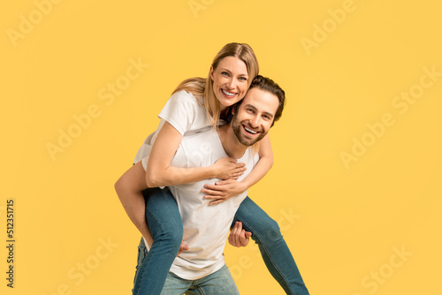 Glad smiling millennial caucasian woman on man on back in white t-shirt, enjoy moment, have fun at free time