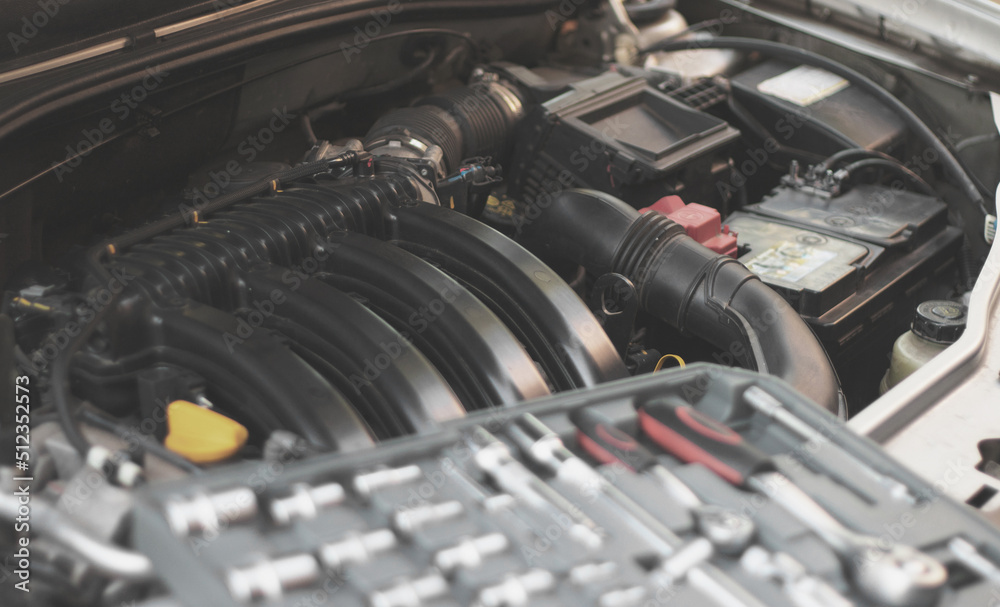 A set of socket wrenches lies on the internal combustion engine of a car in the engine compartment. A set of socket wrenches lies on the internal combustion engine of a car in the engine compartment.