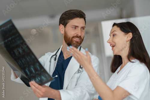 Two doctors in uniform look and discuss an X-ray or MRI scan of the patient spine