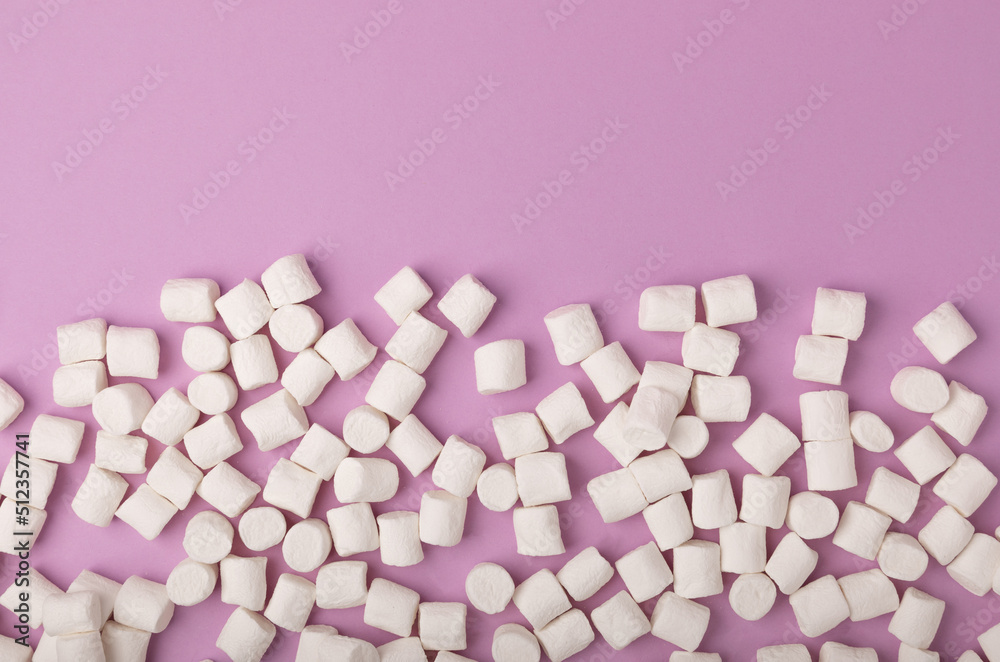 Loose marshmallows on a lilac background. White marshmallow flat lay. Sweets and snacks for a snack. Chewing candies close-up. Copy space. Place for text. Winter food concept. Loose marshmallows on a lilac background. White marshmallow flat lay. Sweets and snacks for a snack. Chewing candies close-up. Copy space. Place for text. Winter food concept.